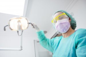 a dental professional wearing personal protective equipment and adjusting the light