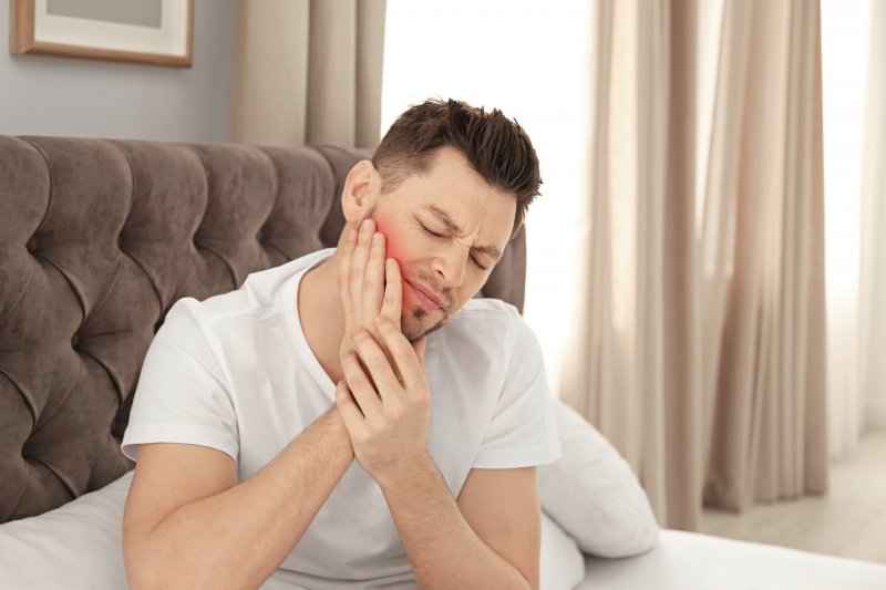 Man with sleep apnea nursing jaw pain in bed