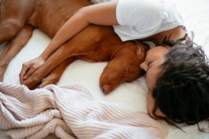 Woman sleeping next to her dog.